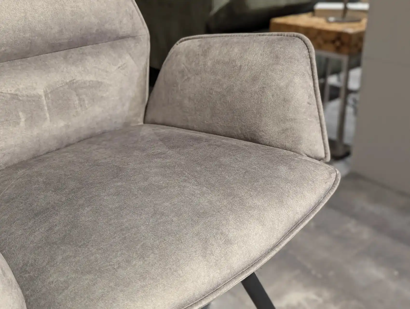 Nahaufnahme von der Armlehne des Stuhls. Klare Aufnahme vom grauen Stoffbezug.